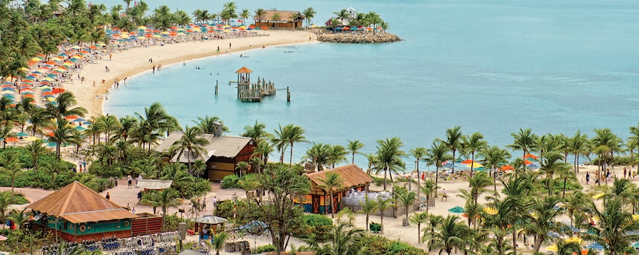 A crescent shaped beach area features cabanas, lots of umbrellas and crystal clear water