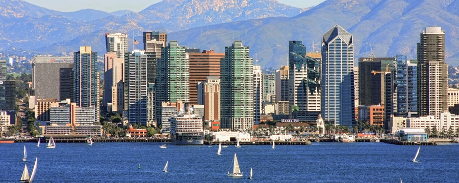 Boats float in the ocean near a city and mountains